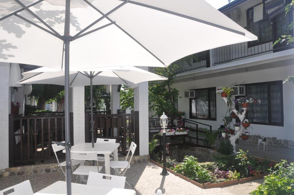 a white table and chairs under an umbrella on a patio at КИПАРИС комнаты для отпуска in Betta