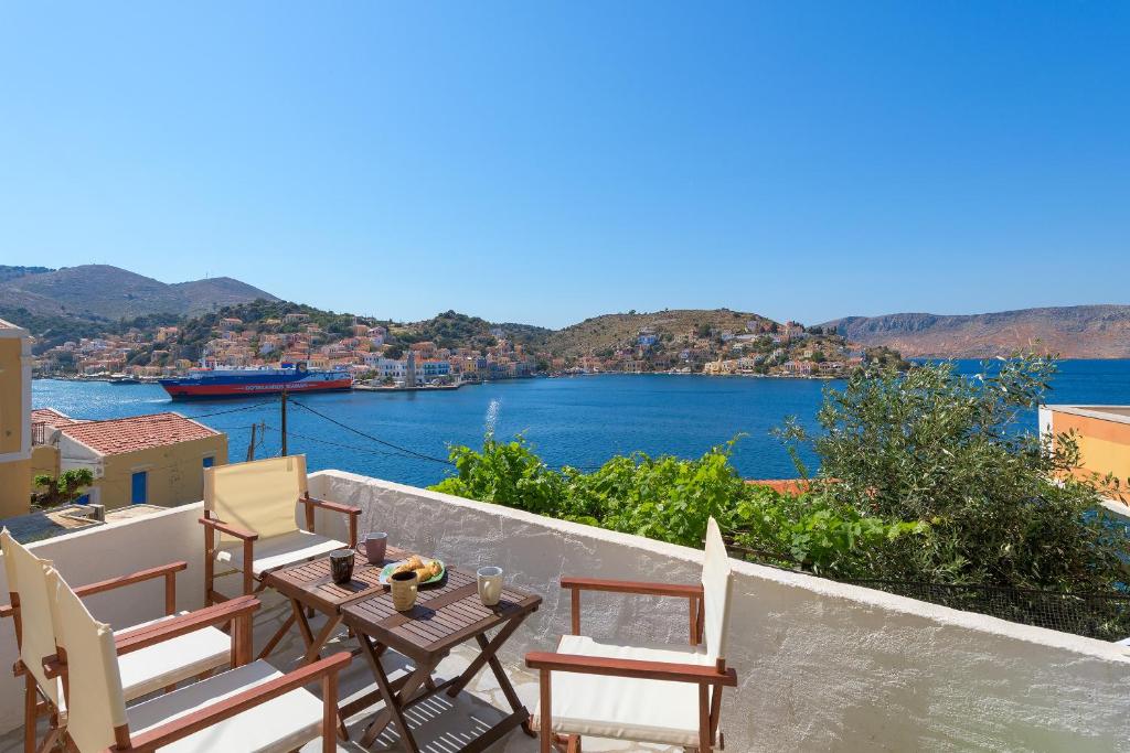 a balcony with chairs and a table with a view of the water at Blue Wave Aigli Villa in Symi