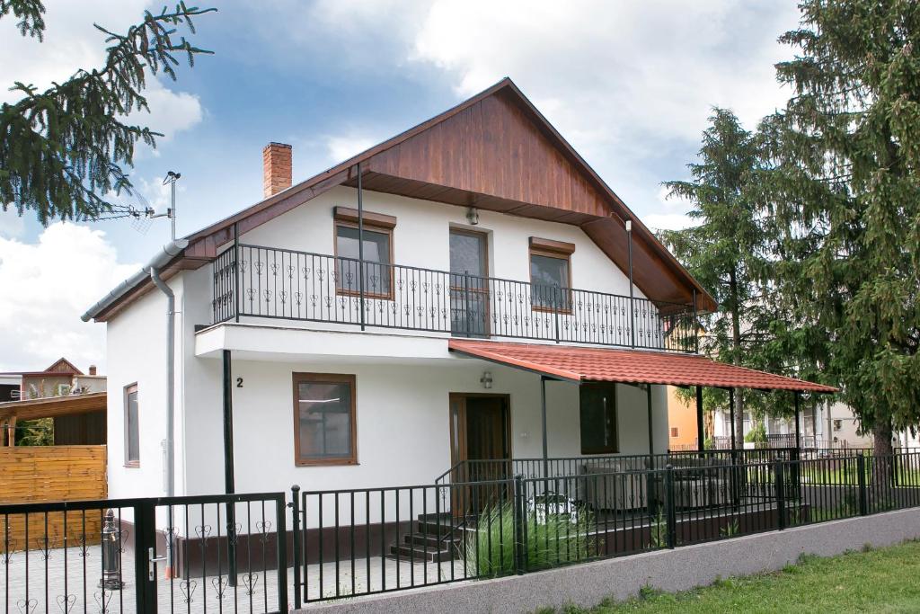 a white house with a red roof and a black fence at Starlight Apartment in Mezőkövesd