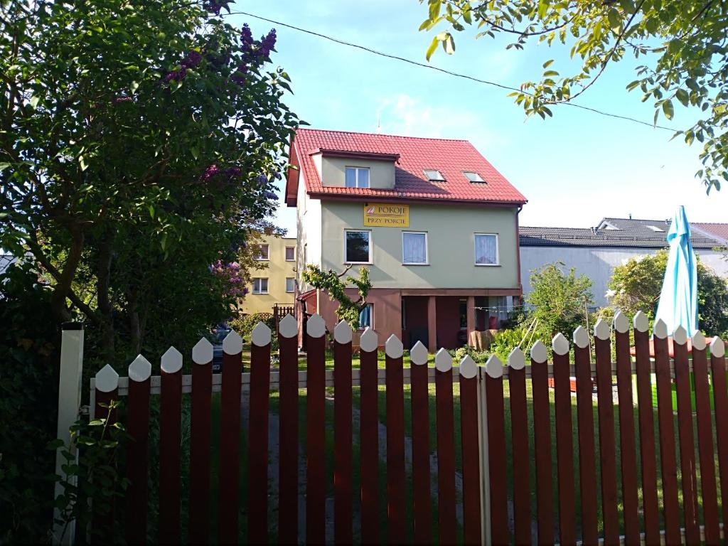 a fence in front of a house with a building at Noclegi - Przy Porcie in Łeba