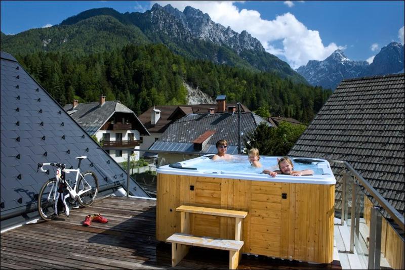 Ein paar Leute in einem Whirlpool auf einer Terrasse in der Unterkunft House Neza in Kranjska Gora