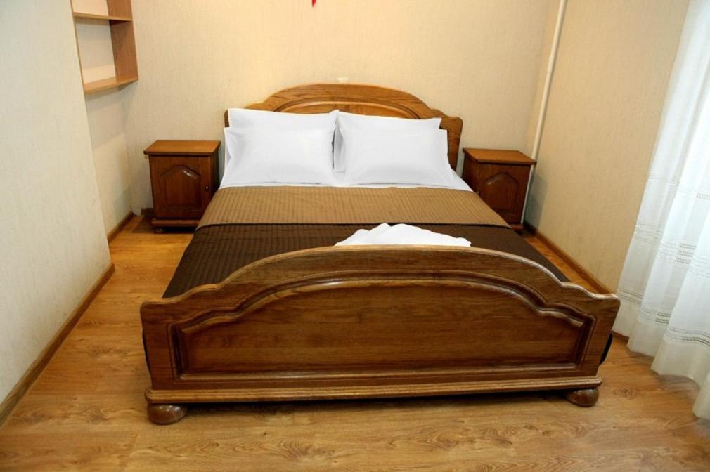 モスクワにあるBarclay Apartmentのベッドルーム1室(木製ベッド1台、ナイトスタンド2台付)