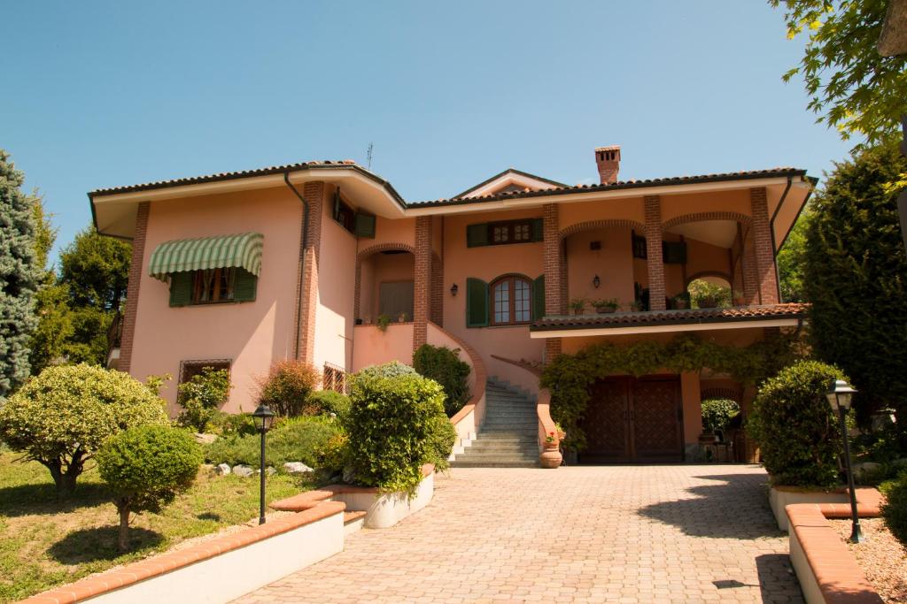 ein großes rosafarbenes Haus mit Auffahrt in der Unterkunft Villa Anselma in Novello