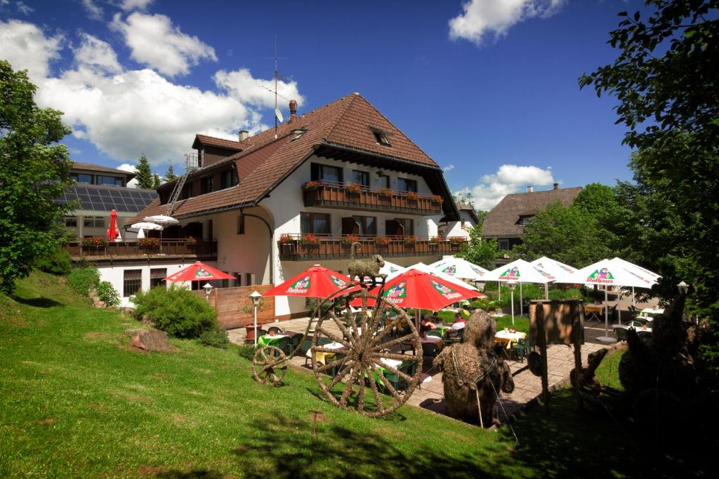 un bâtiment avec des parasols rouges et blancs dans l'herbe dans l'établissement Hotel Cortina, à Höchenschwand