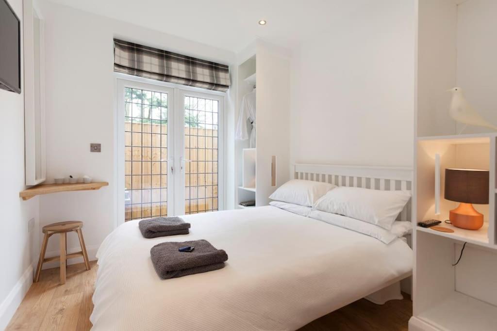 a white bedroom with a large bed with two towels on it at The Woodpecker Snug in Nottingham