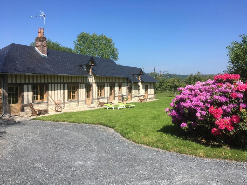 L'auberge du Mont في Le Breuil-en-Auge: منزل أمامه زهور وردية