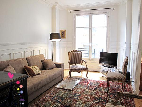 a living room with a couch and a tv at Champs Elysees Argentine CityCosy in Paris
