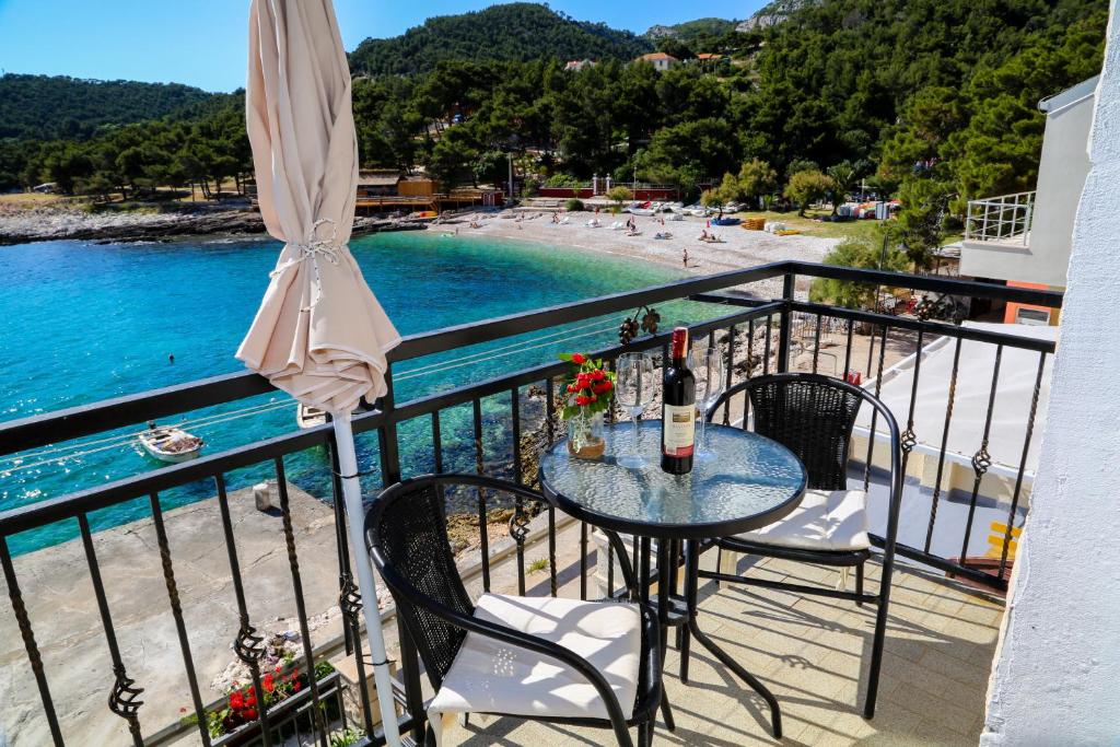 a table and chairs on a balcony with a view of a beach at Duje Apartments Milna in Milna