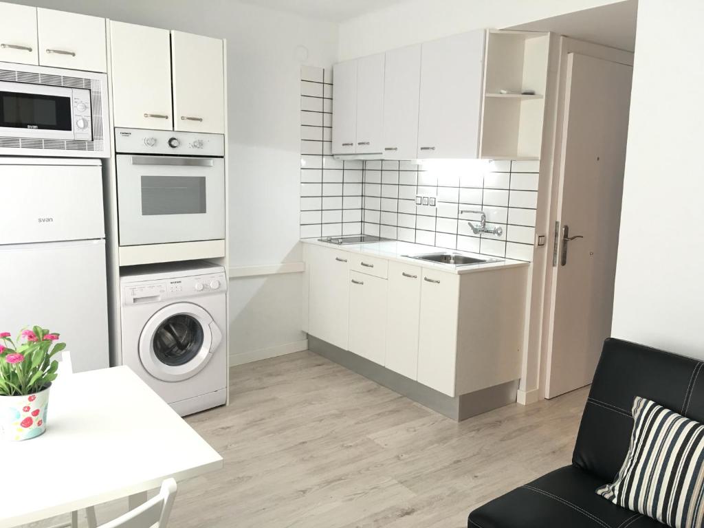 a kitchen with white cabinets and a washer and dryer at Aiguaneu Sa Carbonera in Blanes