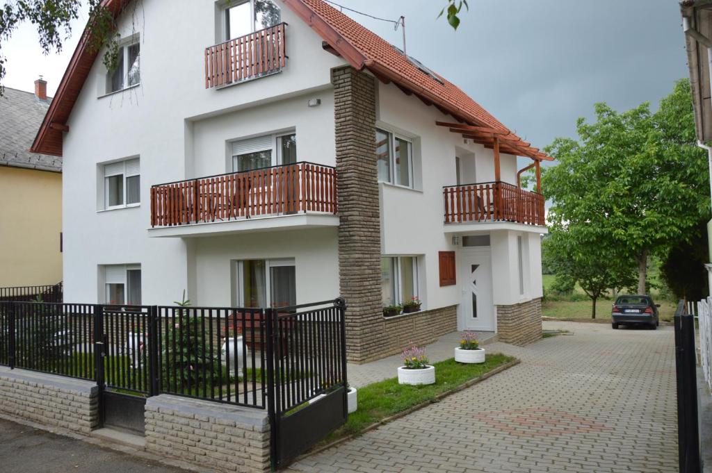 a white house with red balconies and a driveway at Varga Apartman Hévíz in Hévíz