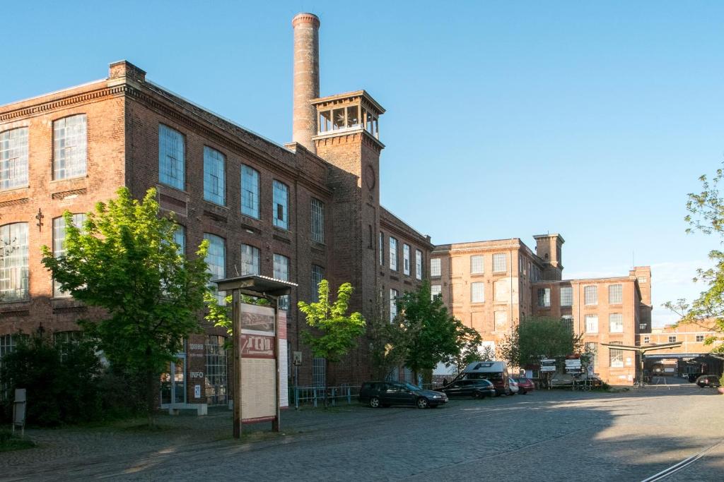 ein altes Backsteingebäude mit einem Uhrturm auf einer Straße in der Unterkunft Meisterzimmer in Leipzig