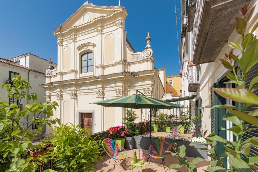 un edificio con sombrilla y sillas delante de él en Roof Garden en Salerno