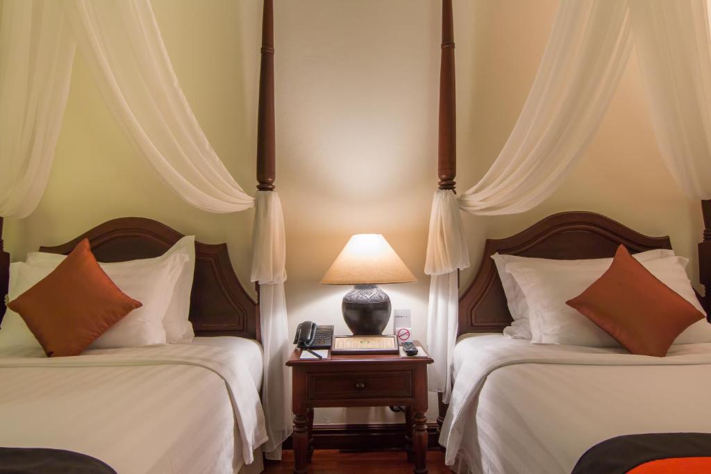 a bedroom with two beds and a lamp on a table at Palace Residence & Villa Siem Reap in Siem Reap