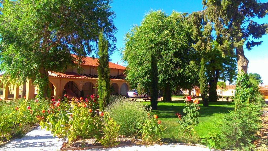 un jardín con flores y árboles frente a un edificio en La Aldea Colorada Casa Rural, en Mota del Marqués