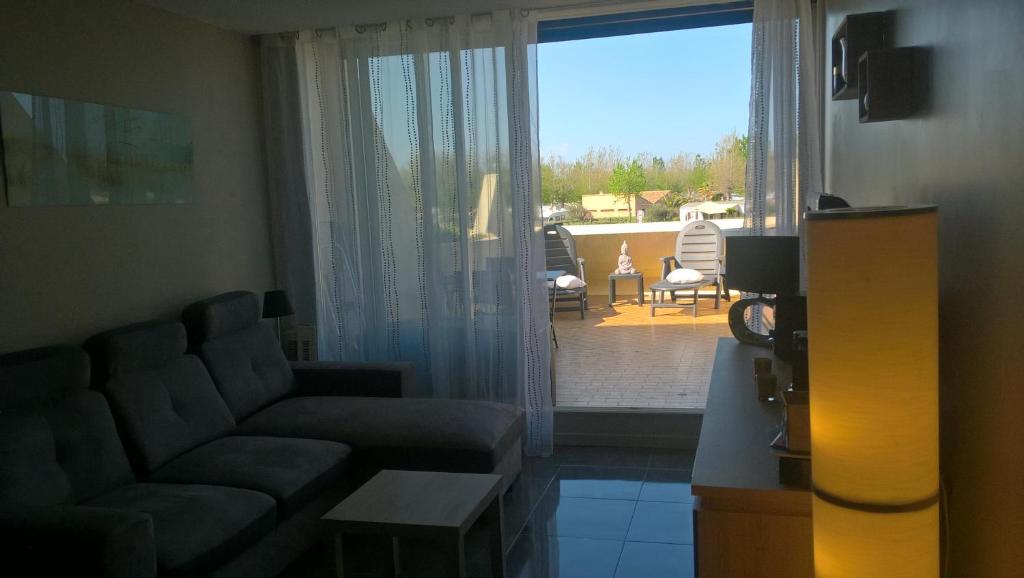 un salon avec un canapé et une porte coulissante en verre dans l'établissement Heliopolis Village Naturiste, au Cap d'Agde