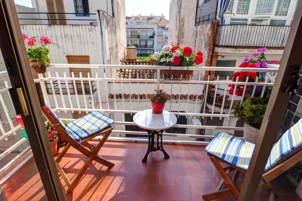 balcón con mesa, sillas y flores en Aquarium Apartment by Hello Homes Sitges, en Sitges