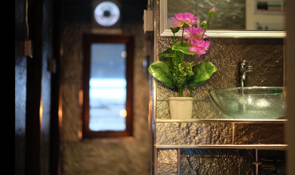 バンコクにあるPhobphan Hostelの洗面台と鉢植えの植物が備わるバスルームカウンター