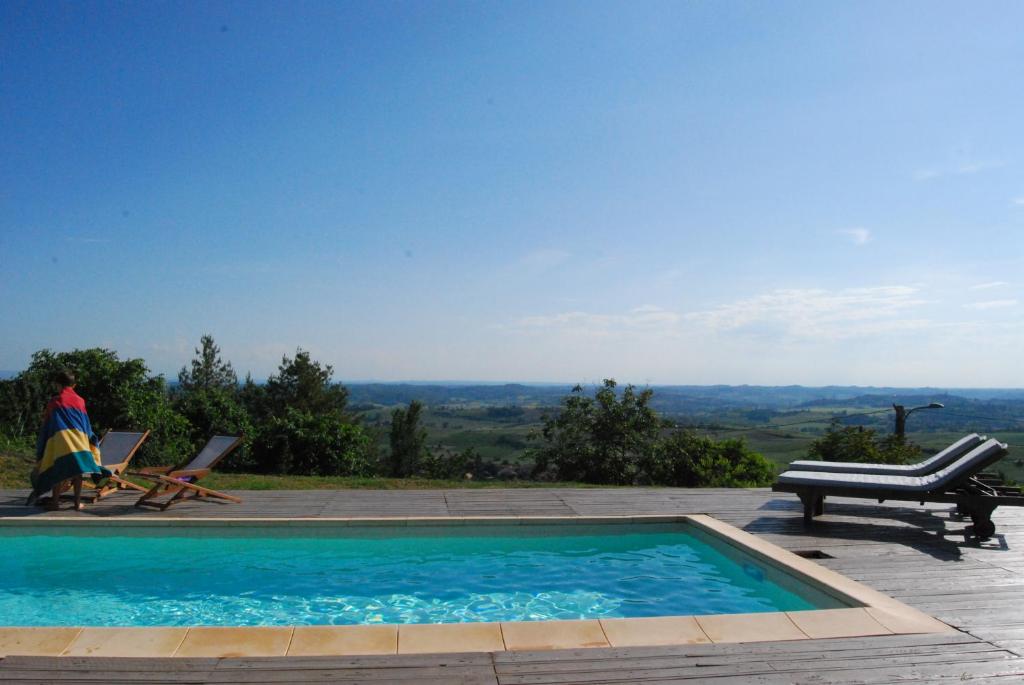 a swimming pool with a table and a person sitting in a chair at Casale Osvalda in Alfiano Natta