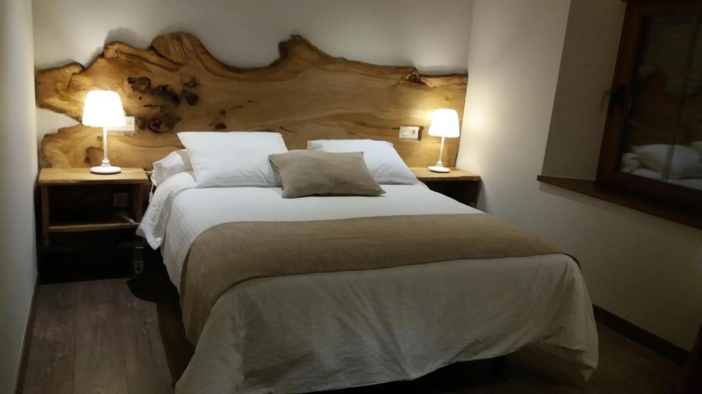 een slaapkamer met een groot bed met 2 lampen bij Hotel Rural El Yunque in Tarilonte