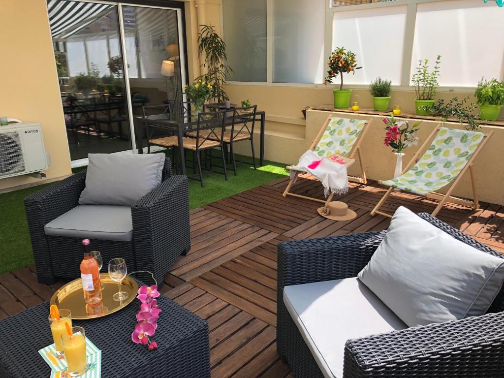 a patio with wicker furniture and a table and chairs at Appartement Cosy Calme Central-Terrasse Proche Palais in Cannes