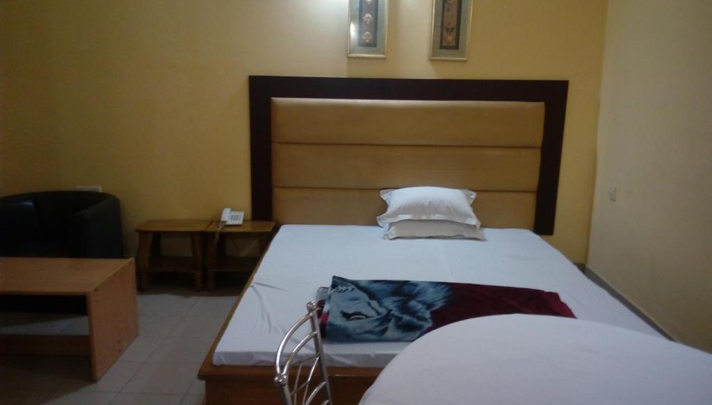 a bedroom with a large bed with a wooden headboard at Royal Park Residential Hotel in Chittagong