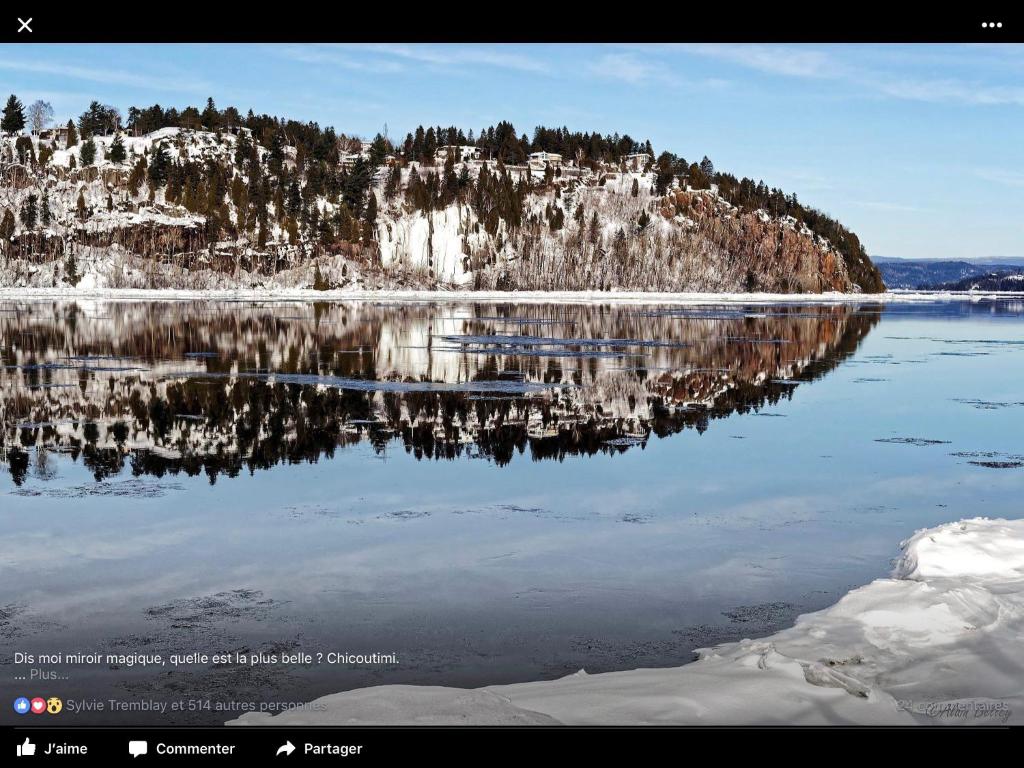 a reflection of a mountain in the water at Auberge Centre Ville in Saguenay