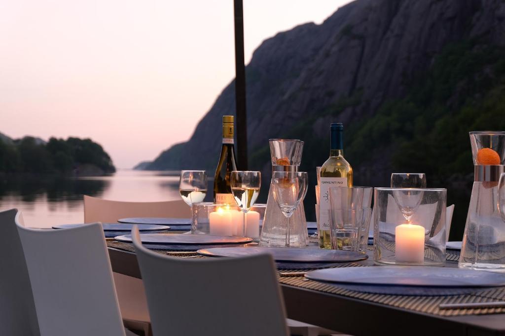 a table with wine bottles and glasses and candles at Logbua - House on the Sea in Åna-Sira