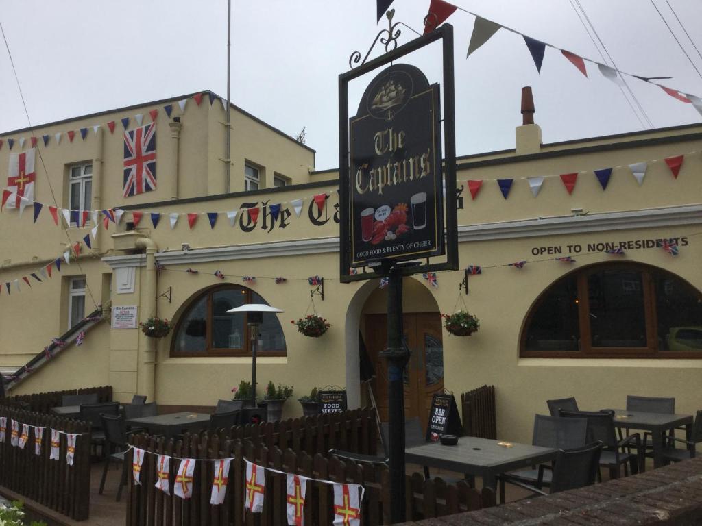 un restaurante con mesas y sillas frente a un edificio en The Captains, en St Martin Guernsey