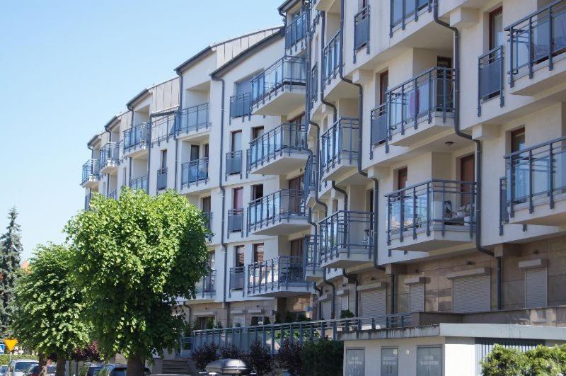 a building with balconies and a tree in front of it at Apartamenty Maki Marea in Międzyzdroje