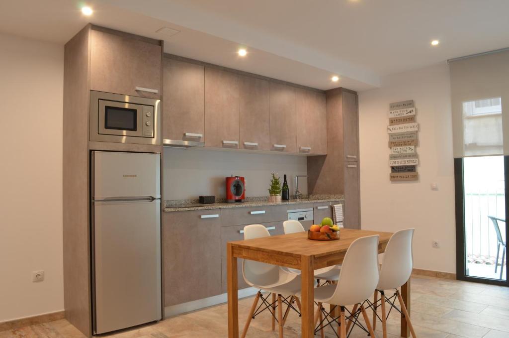 ロザスにあるArkadia Apartaments 2.2のキッチン(木製テーブル、白い椅子付)