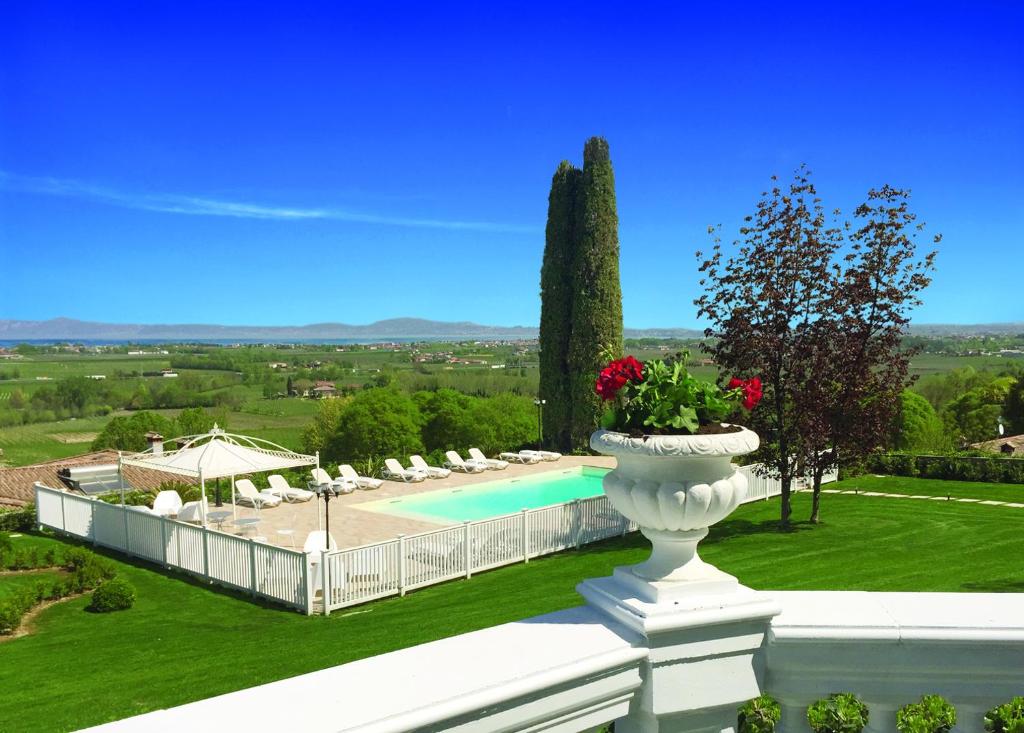 un gran jarrón blanco con flores en una valla blanca en Relais Villa Belvedere & SPA ONLY ADULTS en Pozzolengo