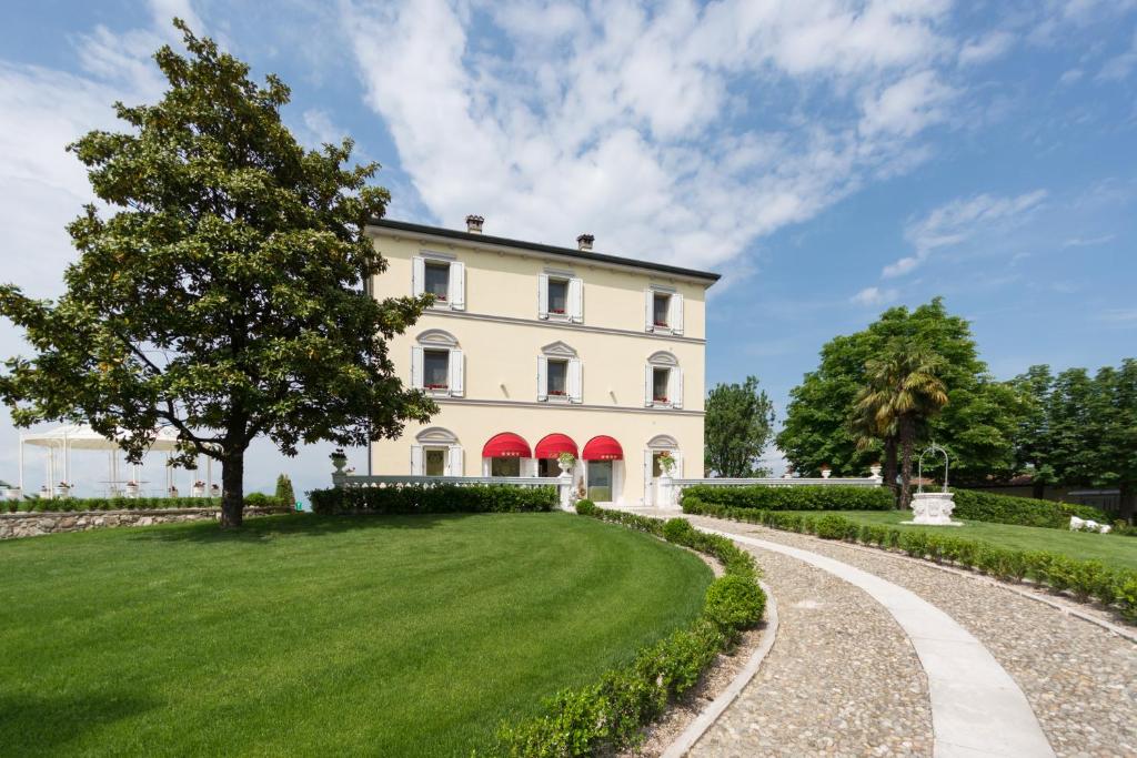 zewnętrzny widok na duży biały dom z podjazdem w obiekcie Relais Villa Belvedere & SPA ONLY ADULTS w mieście Pozzolengo