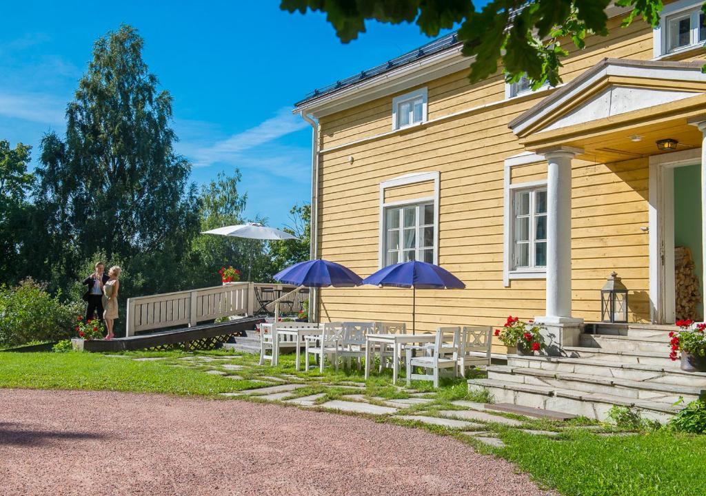 uma casa com mesas e guarda-sóis em frente em Koivulan Kartano em Lohja