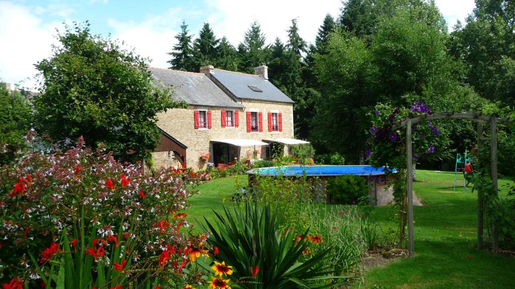 una casa con ventanas rojas y un jardín con flores en Chambres d'hôtes Le Bas Rassinoux en Saint-Ouen-des-Alleux