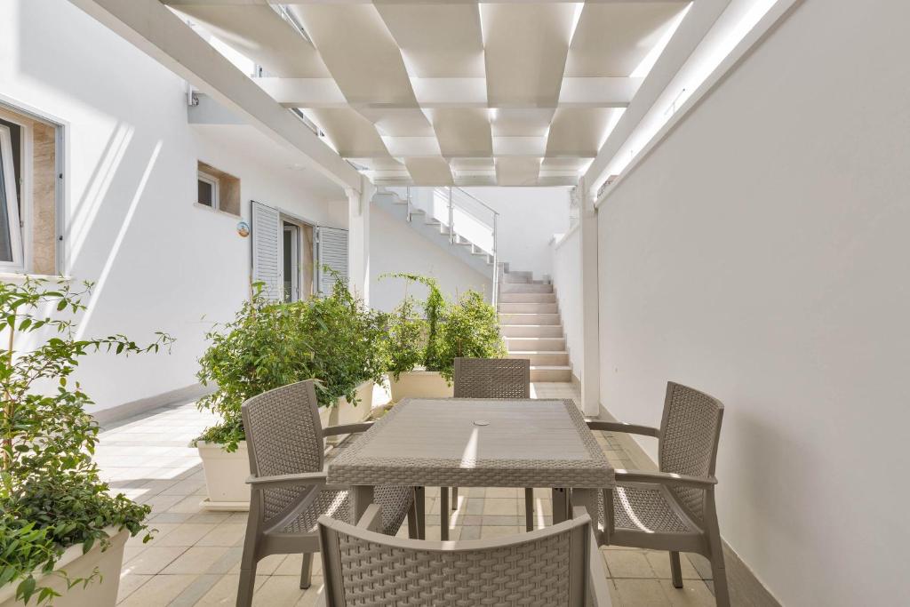 una mesa y sillas en un patio con plantas en Residence Pianeta Mare, en Torre Lapillo