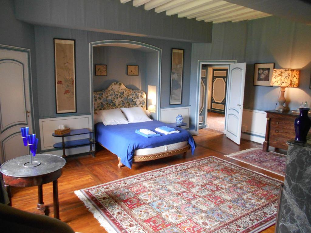 a bedroom with a bed with a blue comforter at Le Château d'Ailly in Parigny