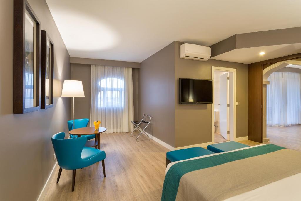 a hotel room with two beds and a table and chairs at AP Oriental Beach - Adults Friendly in Portimão