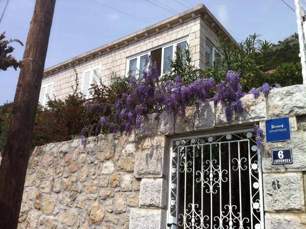 une maison avec des fleurs violettes au-dessus d'un mur en pierre dans l'établissement Apartments Jelen, à Dubrovnik