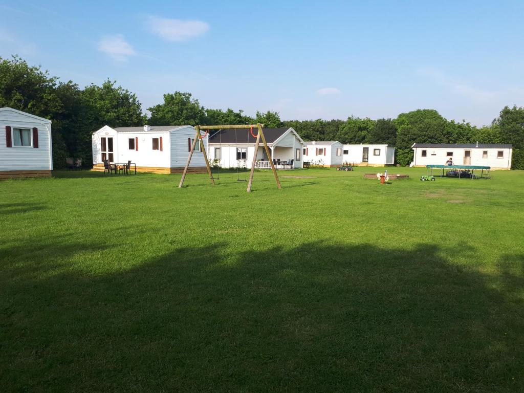 une grande cour avec une aire de jeux et des maisons blanches dans l'établissement Camping De Koehoorn, à Meliskerke