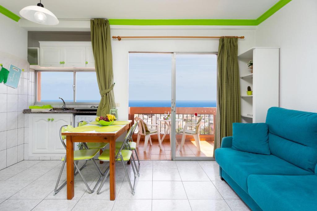 Apartamento vistas al mar Valle Luz في بويرتو دي لا كروث: غرفة معيشة مع طاولة وأريكة زرقاء
