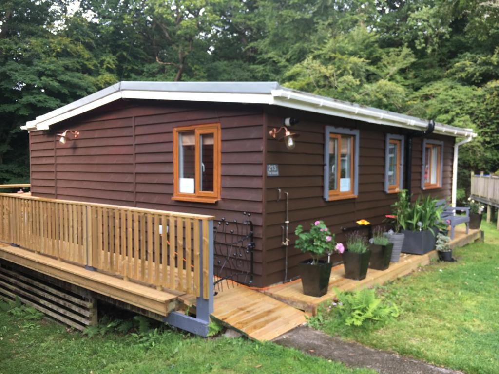 a small cabin with a porch in a yard at Scarlett Cabin Glan Gwna in Caernarfon