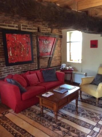 a living room with a red couch and a table at Ancien Relais de Poste in Collandres-Quincarnon