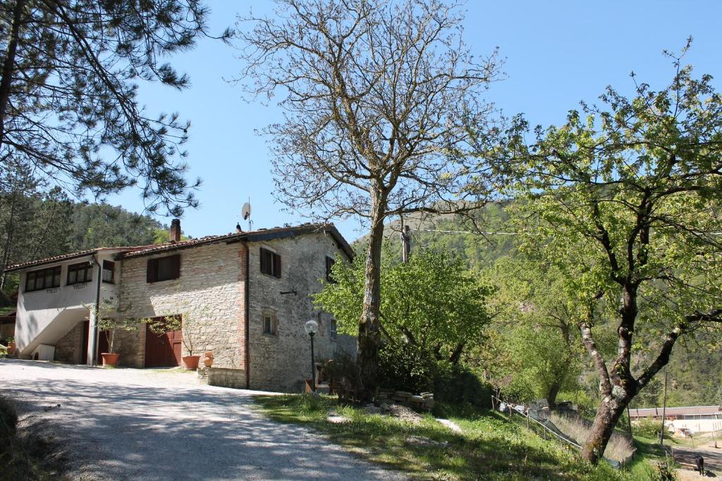 una vista exterior de una casa de piedra con árboles en B&B Paradiso, en Gubbio