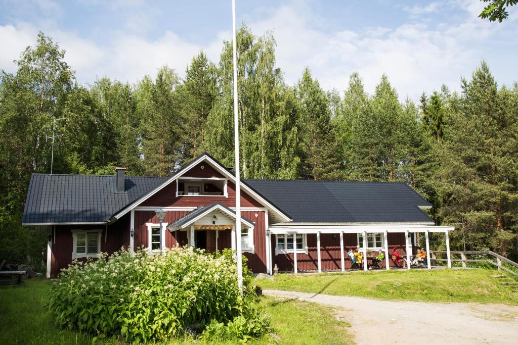 czerwony dom z czarnym dachem w obiekcie Männikkölän Pirtti w mieście Nurmes