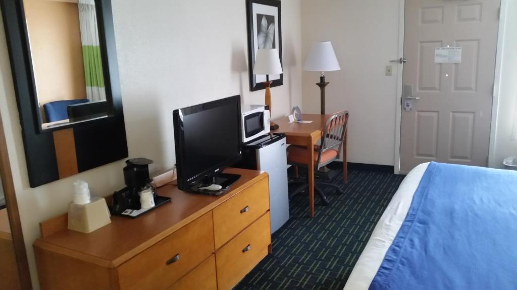 a hotel room with a bed and a desk with a television at Days Inn by Wyndham Chattanooga/Hamilton Place in Chattanooga