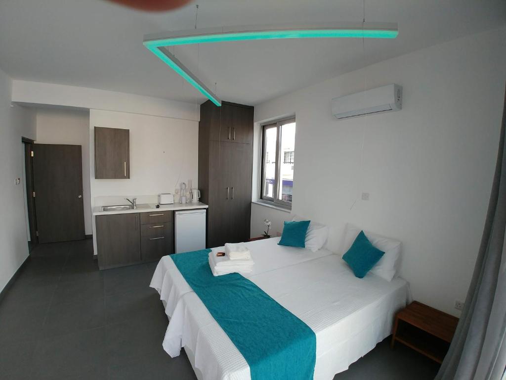 ein Schlafzimmer mit einem großen weißen Bett mit blauen Kissen in der Unterkunft Memory Apartments in Ayia Napa