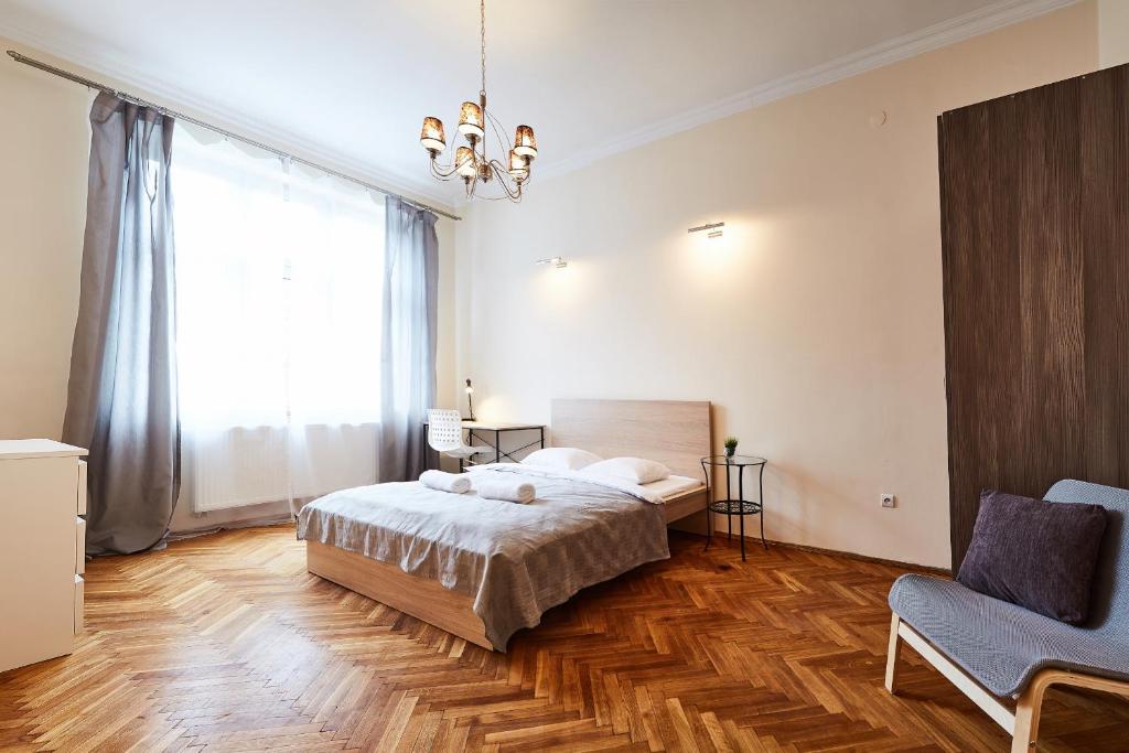 a bedroom with a bed and a chair and a window at Modern Apartments in Krakow