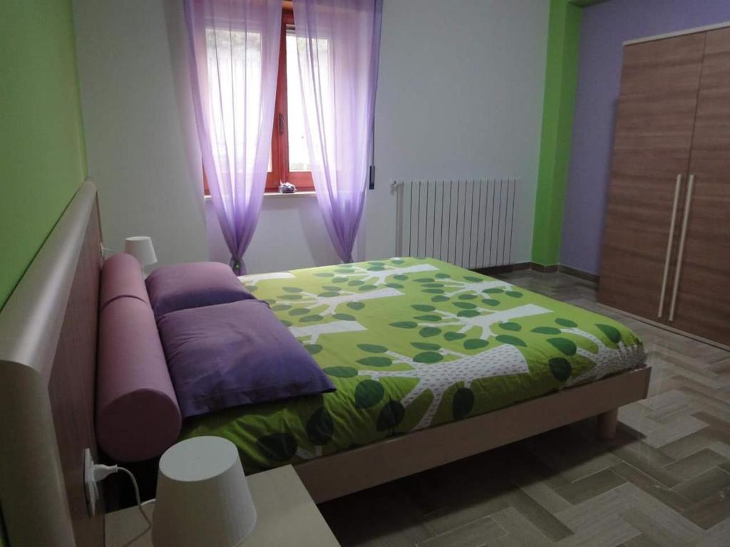 1 dormitorio con 1 cama con almohadas moradas y verde en Le Stagioni, en Spezzano della Sila