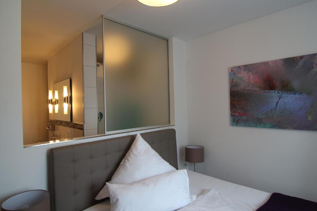 1 dormitorio con espejo y 1 cama con almohadas blancas en Hotel & Restaurant Arnoldusklause, en Düren - Eifel