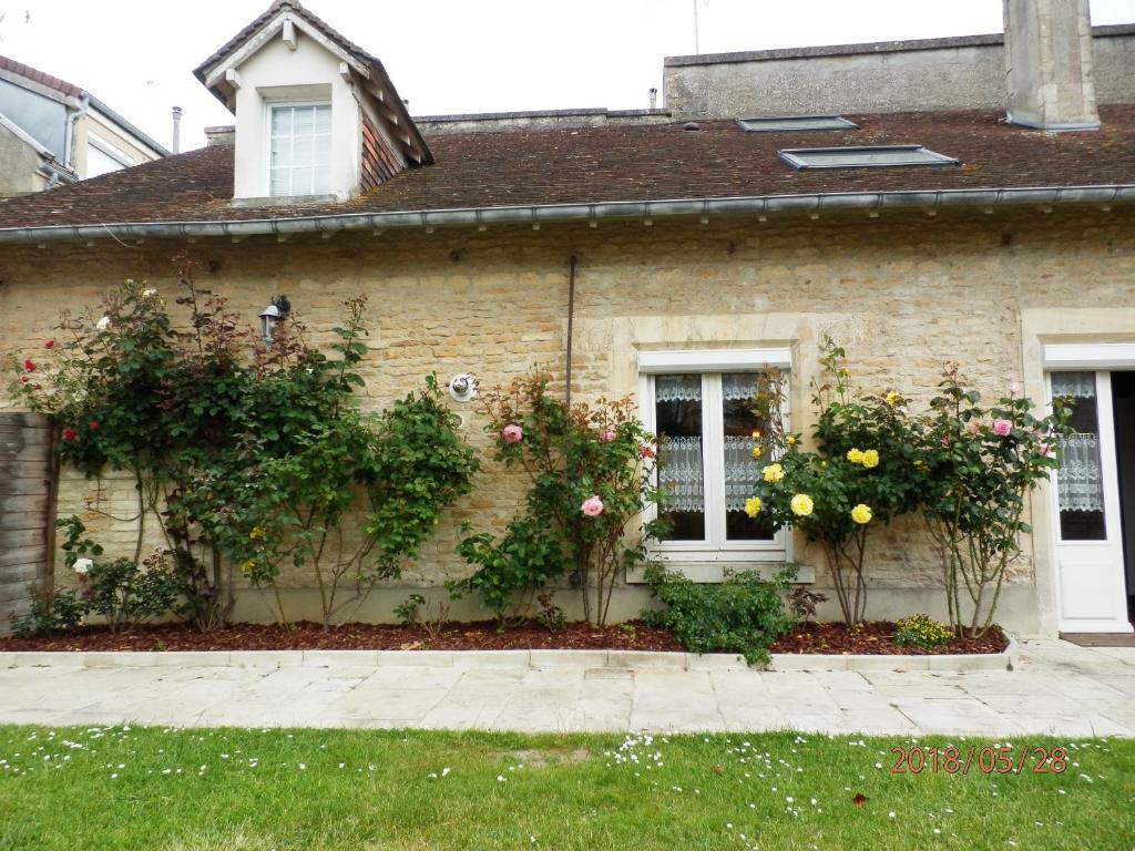 a house with roses on the side of it at Maison Studios & Appartements Les 4 Vents in Luc-sur-Mer